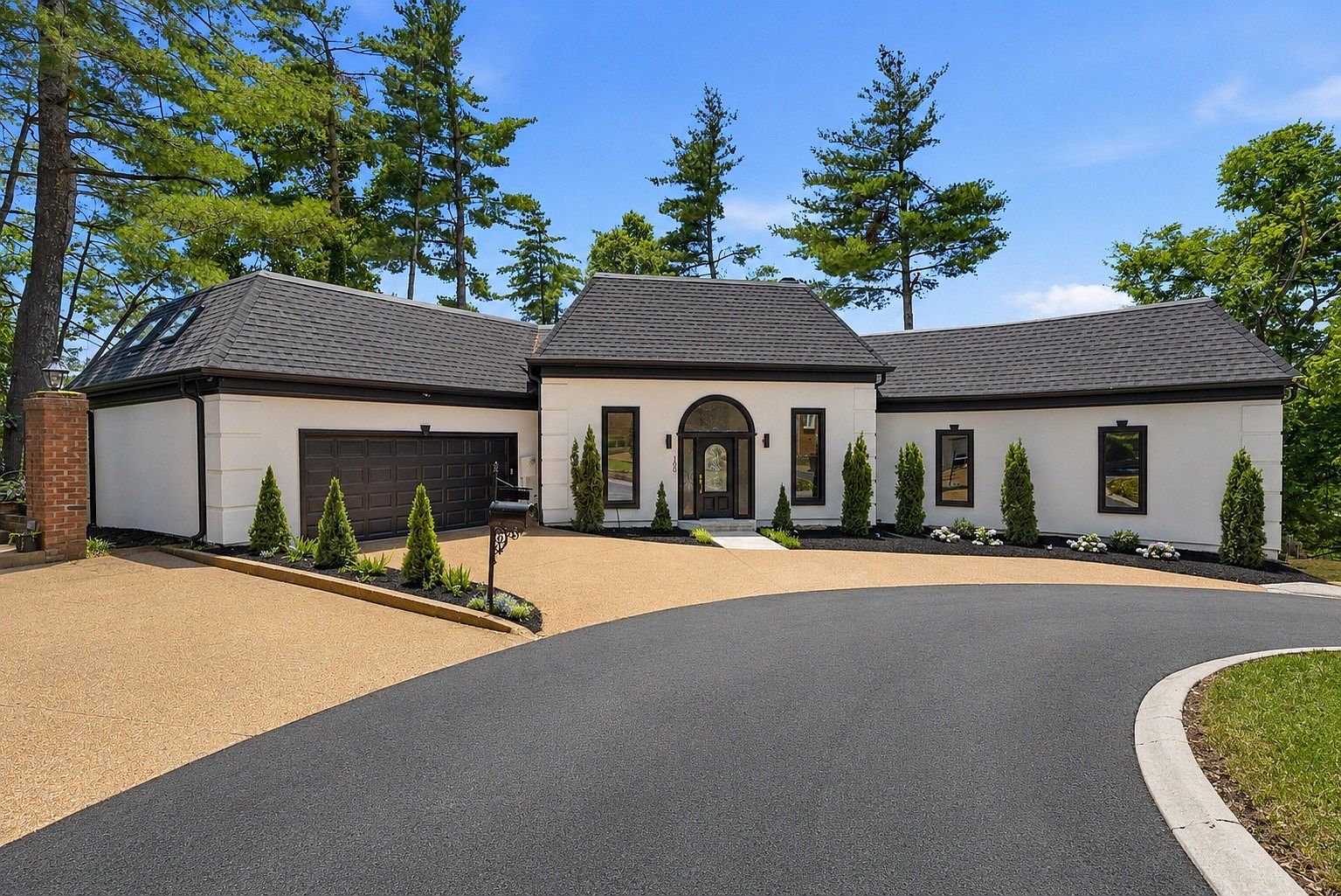 Daytime front elevation of 105 Burlington Ct showing the arched entry, dark garage doors, and the paved cul-de-sac approach
