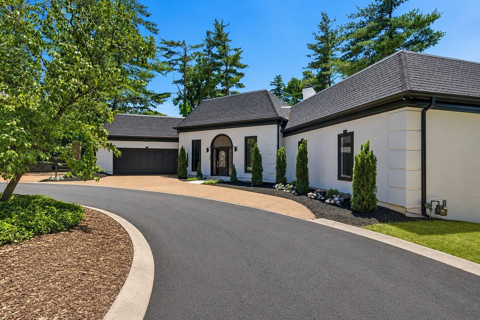 Angled approach to 105 Burlington Ct showing the curved driveway, dark mulched bed, and the home's side elevation